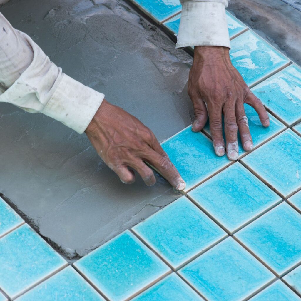 pool installation tech carefully placing blue pool tiles